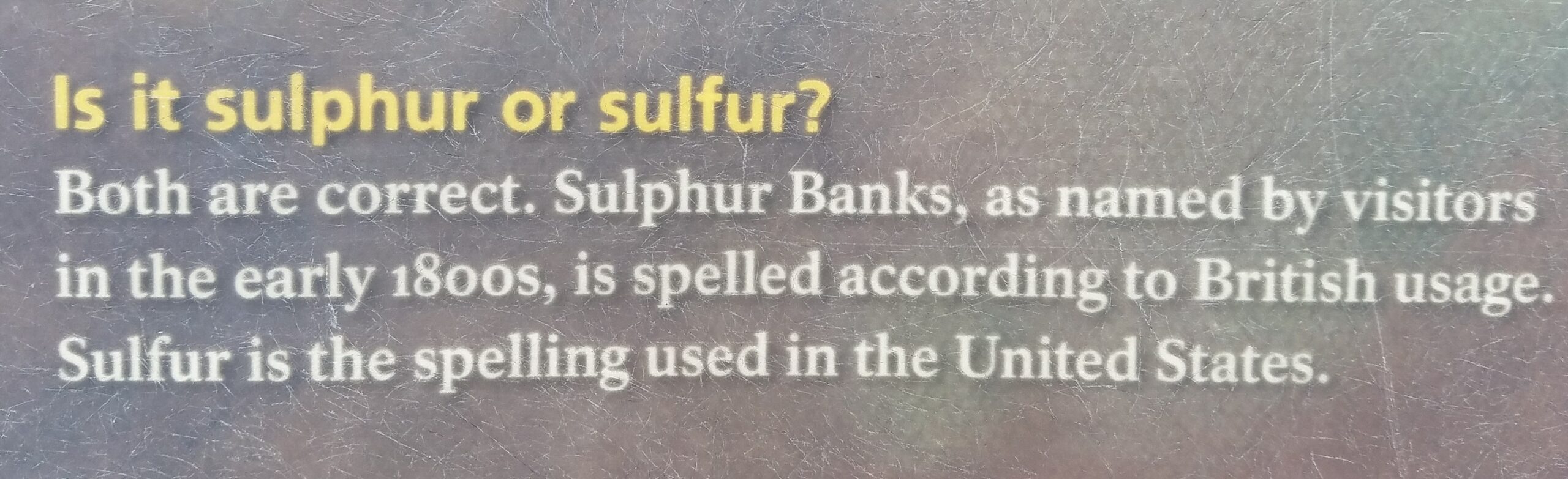 A sign that discuss British vs. US spellings: "Is it sulfur or sulphur? Both are correct. Sulphur Banks, as named by visitors in the early 1800's, is spelled according to British usage. Sulfur is the spelling used in the United States.