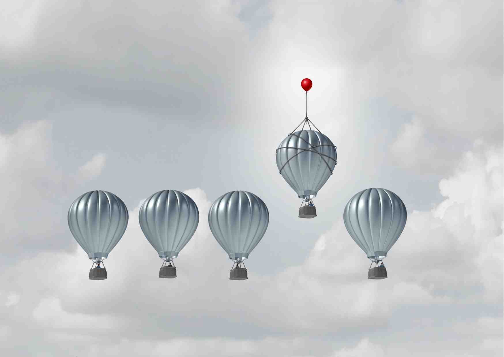 A picture of 5 hot air balloons in line with one being raised above the rest by a small red balloon 